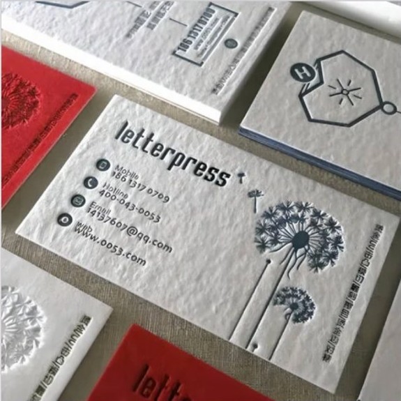Debossed letterpress cards in red and white cotton paper with dandelion illustration.