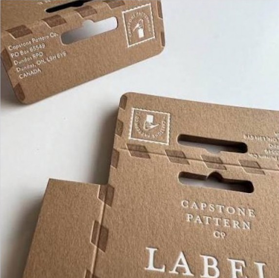 Kraft cardboard hanging labels with debossed pattern branding.