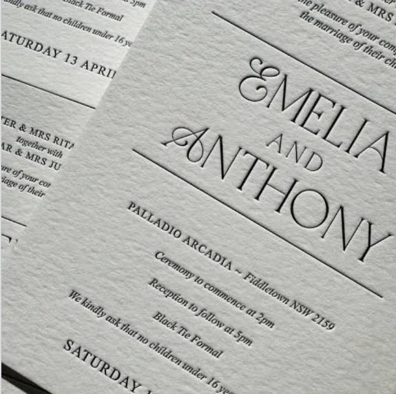 Close-up of a debossed wedding invitation showing the couple's names in serif type.